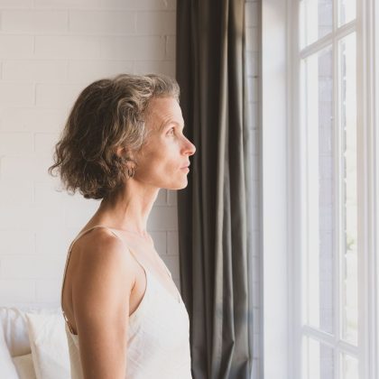 Older woman with short hair looking outside a bright window